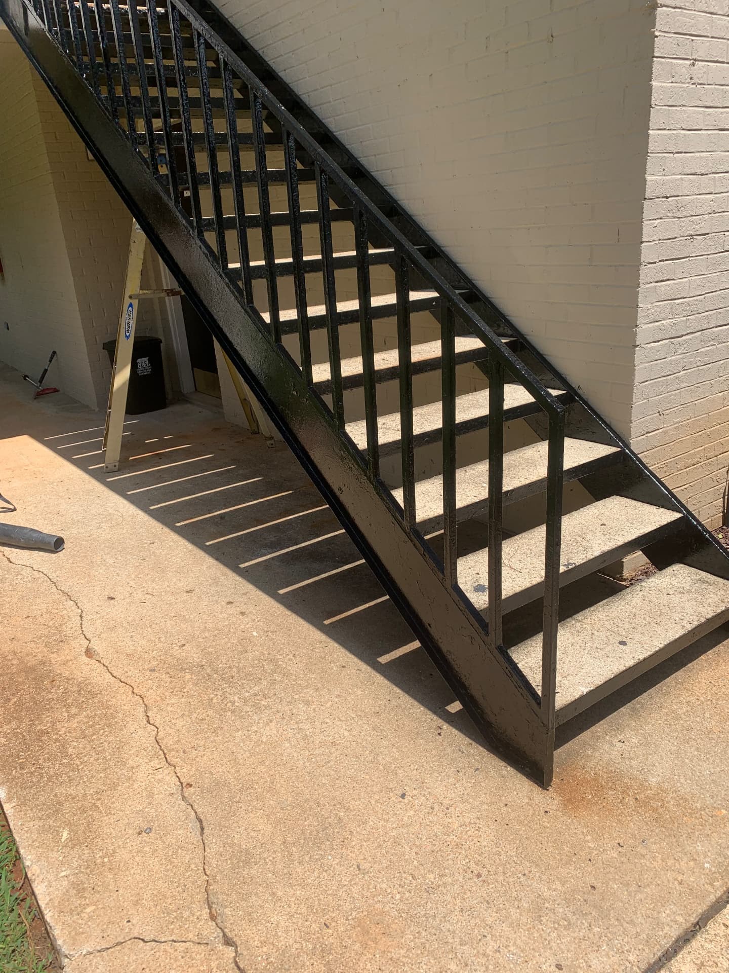 Black steel exterior stair and railing beside a brick building