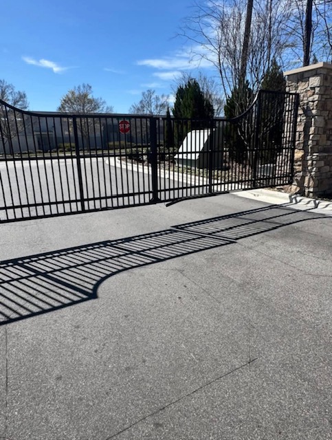 Black metal driveway gate between stone pillars